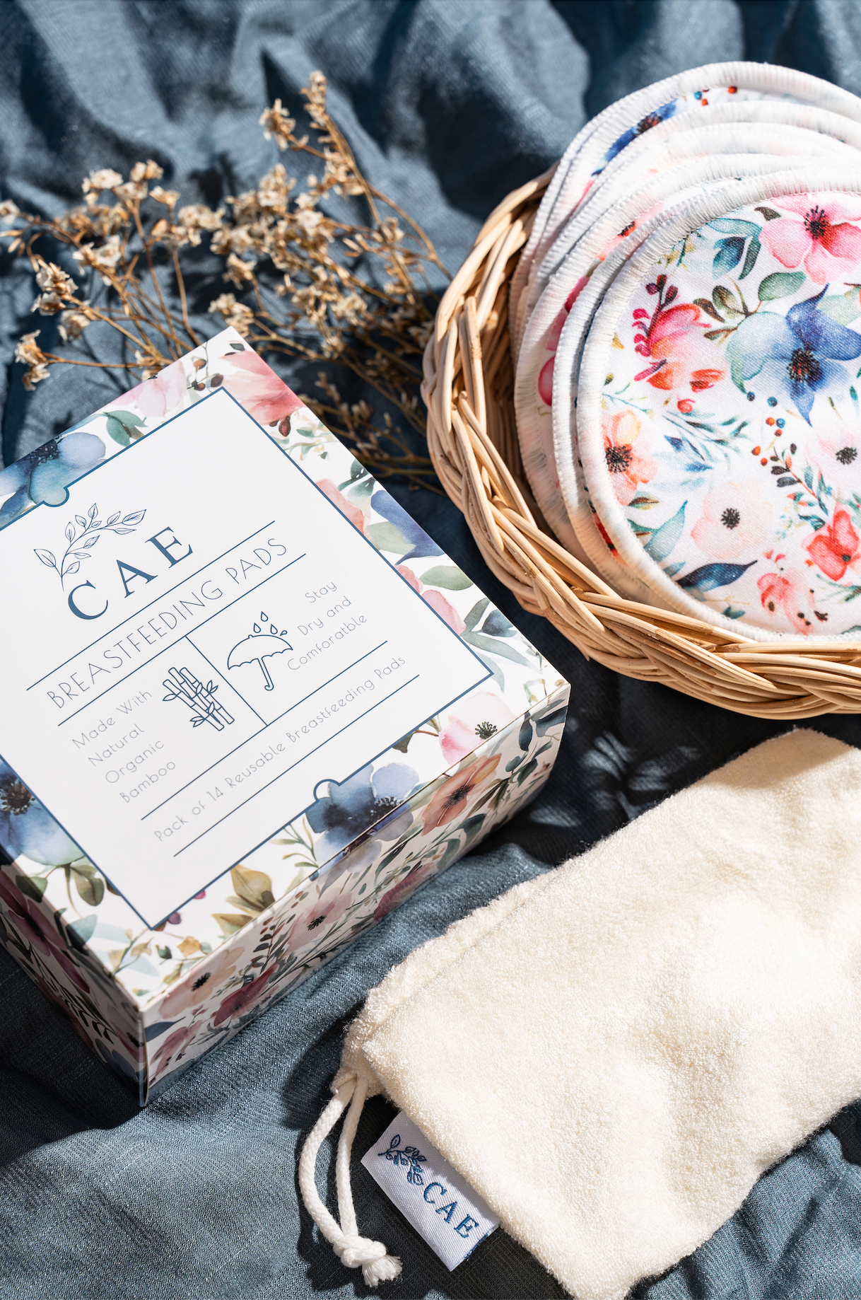 Reusable CAE bamboo nursing pad in a woven basket with lavender and linen