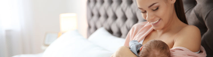 Smiling mum breastfeeding her newborn baby in bed, Silverette benefits banner