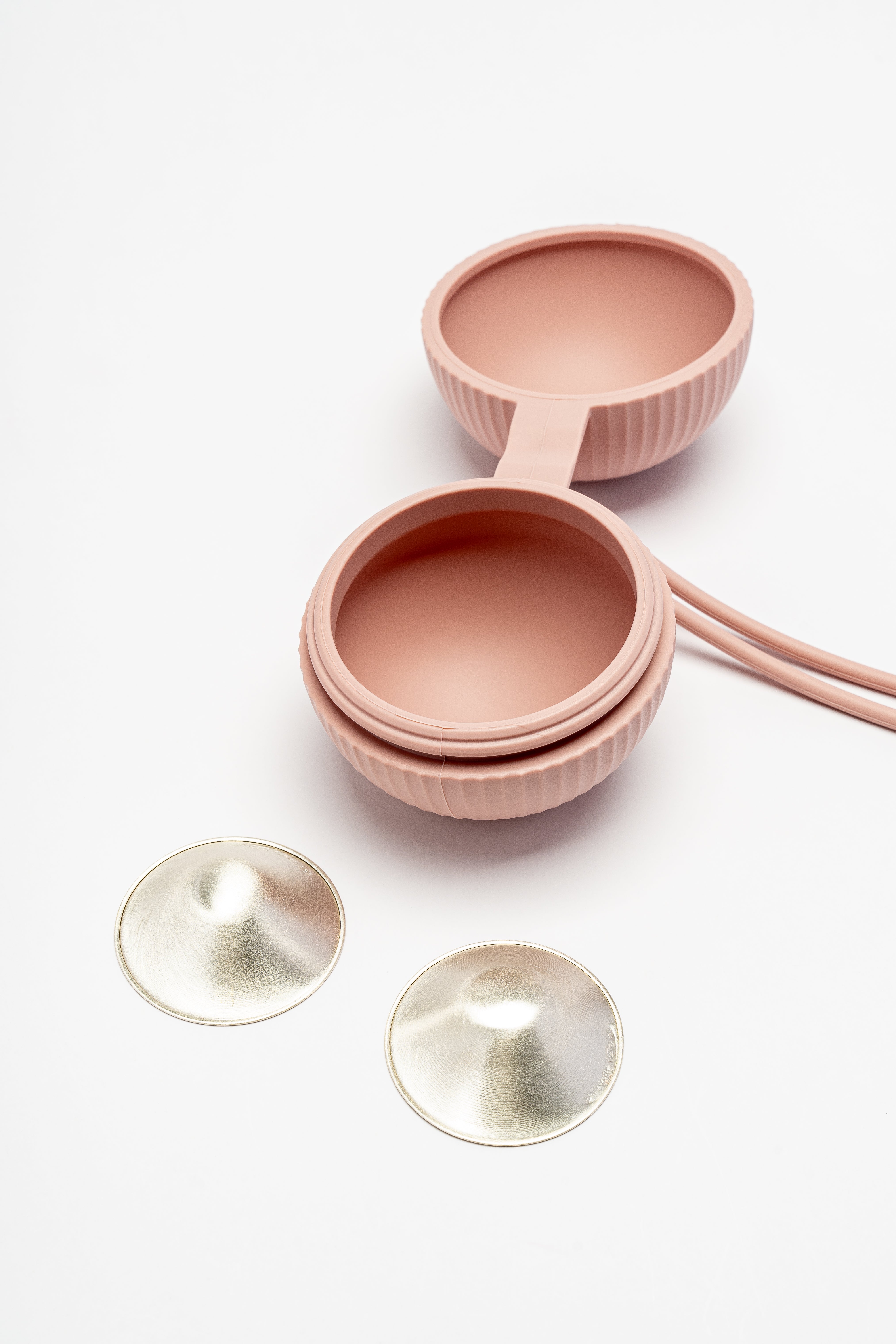 Silverette Happy Nipples pink silicone holder, open, with two Silverette 925 sterling silver nursing cups beside it
